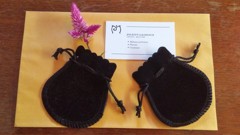K&ouml;nnte beinhalten: Zwei schwarze Samtbeutel mit Kordelzug und einer Visitenkarte mit dem Text "Jocelyn Lachance, Medium, Reiki-Meisterin, Edelmetalle, Steine, Kristalle".