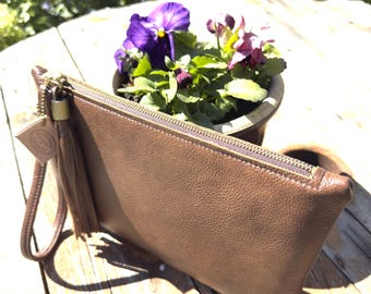 Bolso de mano de piel marrón oscuro con borla y correa para la muñeca.
