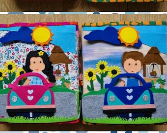 May include: A felt book for children with colorful pages depicting a house, a car, a girl, a boy, and a sun. The pages are decorated with flowers, a fence, and a cloud.