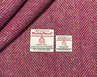 May include: Close-up of a pink and white herringbone tweed fabric with two white labels. The labels read "HAND WOVEN CLOTH Harris Tweed®" and include the Harris Tweed Orb logo. The text on the labels reads "HARRIS TWEED OUTER HEBRIDES OF SCOTLAND 100% PURE NEW WOOL".