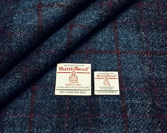Peut inclure: Un gros plan sur un tissu à carreaux bleu et bordeaux avec deux étiquettes blanches. Les étiquettes indiquent "HAND WOVEN CLOTH Harris Tweed®" et comprennent le logo Harris Tweed Orb. Le texte sur les étiquettes indique "HARRIS TWEED OUTER HEBRIDES OF SCOTLAND 100% PURE NEW WOOL".