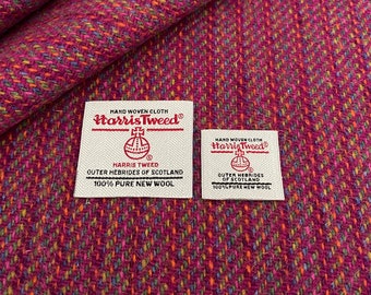 May include: Close-up of a pink and white tweed fabric with two white labels. The labels read "HAND WOVEN CLOTH Harris Tweed®" and include the Harris Tweed Orb logo. The text on the labels also reads "HARRIS TWEED OUTER HEBRIDES OF SCOTLAND 100% PURE NEW WOOL".
