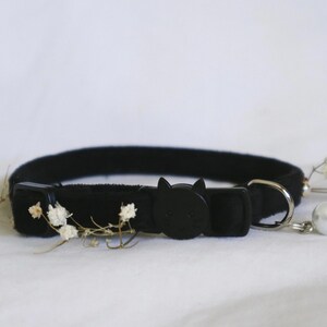 May include: Black cat-shaped breakaway collar with a white pearl charm. The collar is made of soft velvet and has a safety buckle.