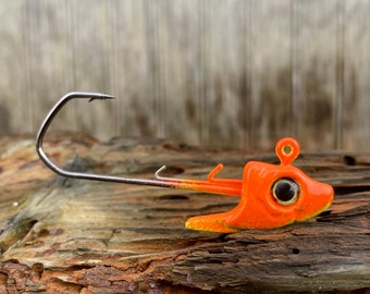 Könnte beinhalten: Orangefarbener und gelber Angelköder mit einem schwarzen Auge und einem silbernen Haken. Der Köder ist so konzipiert, dass er einem kleinen Fisch ähnelt.