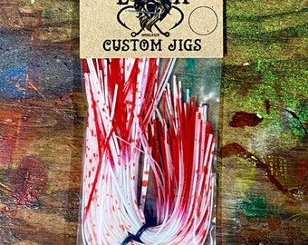 Könnte beinhalten: Eine Packung mit roten und weißen, individuell angefertigten Angelködern mit weißen Punkten. Die Packung ist mit "English Angling E A Custom Jigs" beschriftet.