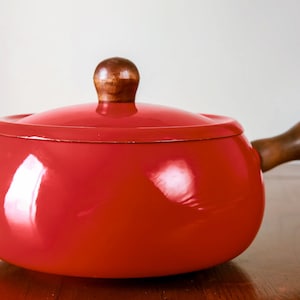 May include: Red enamel fondue pot with a wooden lid and handle.