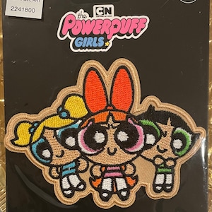 May include: Iron-on patch featuring the Powerpuff Girls cartoon characters. The patch is beige with embroidered details in pink, red, yellow, blue, green, and black. The text "the POWERPUFF GIRLS" is in a white bubble font with a pink outline. The text "CN CARTOON NETWORK" is in white with a black outline. The text "PATCH" is in white with a black outline.