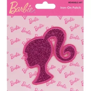 May include: A pink iron-on patch featuring the silhouette of Barbie's head and ponytail. The patch has a glittery texture and is outlined with a darker pink border. The background is pink with the word "Barbie" repeated.