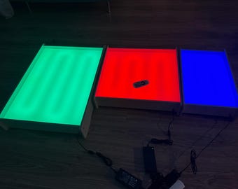 May include: Three light boxes with different colored lights. The box on the left has green lights, the middle box has red lights, and the box on the right has blue lights.