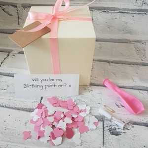 May include: A white gift box with a pink ribbon and a small card that says "Will you be my Birthing partner? x". The box is surrounded by pink and white confetti hearts and a pink balloon.
