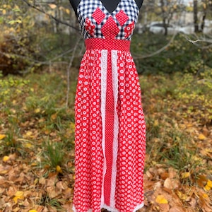 May include: A red and white floral print halter dress with a white lace trim. The bodice features a navy and white gingham pattern and red diamond accents. The dress is displayed on a black mannequin.