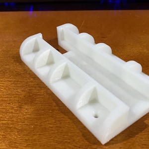 Puede incluir: Soporte de pared de plástico blanco con cinco ranuras para guardar objetos, como herramientas o utensilios. El soporte tiene un pequeño agujero para sujetarlo a una pared.