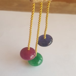 May include: A gold tassel with three dangling beads. The beads are purple, pink, and green.