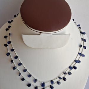 Può includere: Una collana a doppio filo realizzata con perline di pietre preziose blu scuro a forma di goccia su una catena d'argento.