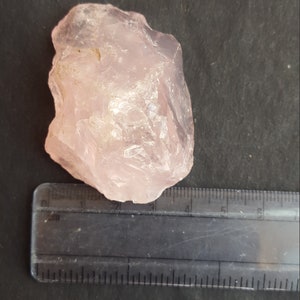 Peut inclure: Un gros cristal de quartz rose brut de couleur rose clair. Le cristal mesure environ 4 cm de large et 5 cm de long.