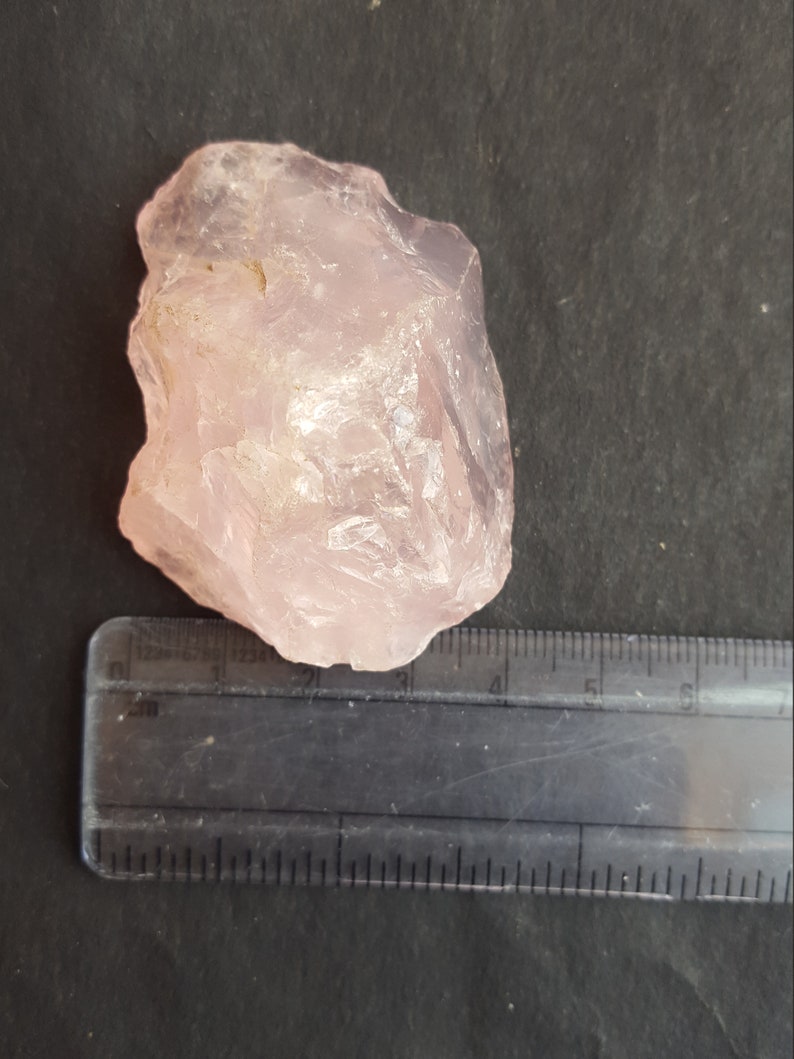 Peut inclure: Un gros cristal de quartz rose brut de couleur rose clair. Le cristal mesure environ 4 cm de large et 5 cm de long.