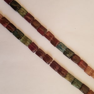 May include: Two strands of square-shaped beads in a variety of colours, including green, brown, red, and yellow.