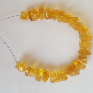 May include: A strand of yellow citrine gemstone beads strung on a silver wire.