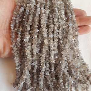 May include: A strand of grey, faceted, crystal beads. The beads are small and have a rough, natural texture. The strand is approximately 46 cm long.