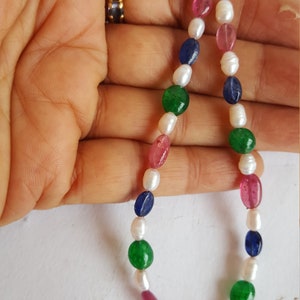 May include: A strand of oval-shaped beads in pink, green, blue, and white. The beads are strung on a thin wire.