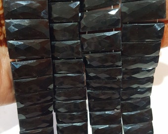 May include: A strand of black faceted gemstone beads. The beads are rectangular in shape and have a polished finish.