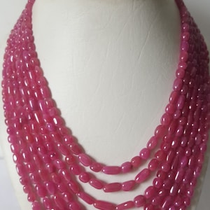Op de afbeelding: Een meerstrengige ketting gemaakt van roze edelsteen kralen. De kralen zijn ovaalvormig en hebben een gladde, gepolijste afwerking.