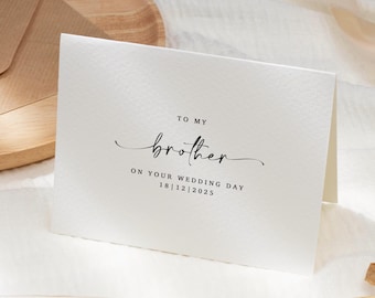 May include: A white card with the words "TO MY brother ON YOUR WEDDING DAY 18|12|2025" in black script. The card is on a white textured surface with wheat stalks and a wooden tray in the background.