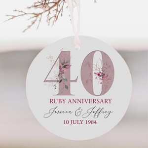 May include: Round white ornament with a pink floral design and the number 40 in the center. The text "Ruby Anniversary Jessica & Jeffrey 10 July 1984" is printed below the number.