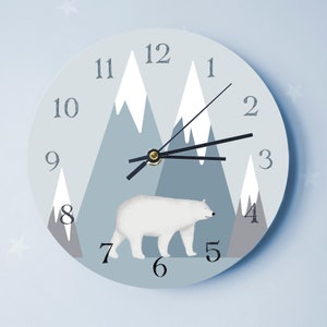 May include: A blue and white clock featuring a polar bear and mountain design. The clock face has black hands and numbers 1 through 12.