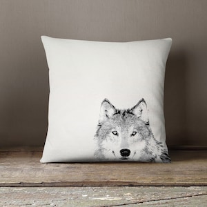 May include: A white cushion with a black and white image of a wolf's face.