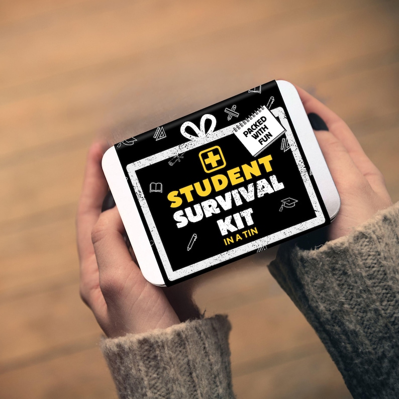 May include: A rectangular metal tin featuring a black and white label with the text "STUDENT SURVIVAL KIT IN A TIN" in yellow and white. The label includes a yellow plus sign, a small notepad graphic with "PACKED WITH FUN" text, and various school-themed icons.