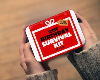 May include: A rectangular metal tin featuring a red label with a white gift bow graphic and a tan tag that reads PACKED WITH FUN. The label text reads 21ST BIRTHDAY SURVIVAL KIT IN A TIN in bold black and white lettering on a red background.