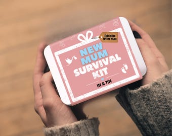 May include: A rectangular metal tin with a pink label featuring a white border and the text NEW MUM SURVIVAL KIT IN A TIN. The label includes a white stork icon, a small blue heart, baby footprint icons, and a brown tag labelled PACKED WITH FUN.