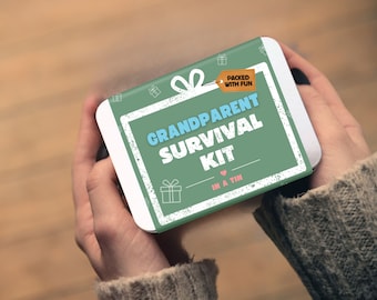 May include: A rectangular metal tin featuring a sage green label with white gift box icons. The text reads GRANDPARENT SURVIVAL KIT IN A TIN in white and light blue, with an orange tag stating PACKED WITH FUN and a small pink heart icon.