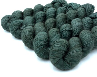 May include: A collection of dark teal yarn skeins, arranged closely together against a white background. The yarn appears soft and textured, ideal for knitting or crochet projects. The skeins are tightly wound, showcasing the yarn's quality.