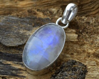 May include: A silver pendant with a large oval moonstone. The moonstone is iridescent with a blue sheen.