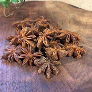 May include: A pile of brown star anise pods on a wooden surface.