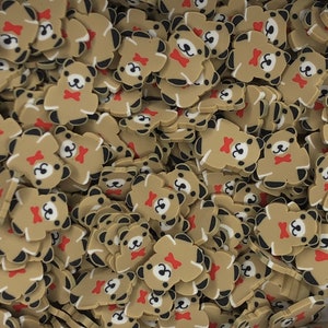 Pode incluir: Um grande monte de pingentes em forma de urso castanho com olhos pretos, narizes brancos e laços vermelhos. Os pingentes são feitos de um material macio e flexível e são perfeitos para adicionar um toque de fantasia a artesanatos e projetos.