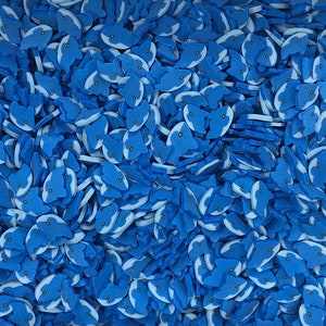 May include: A large quantity of blue and white whale-shaped sprinkles. The sprinkles are made of a soft, pliable material and are perfect for decorating cakes, cupcakes, and other desserts.