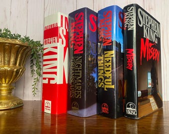 Puede incluir: Cinco libros de tapa dura de Stephen King, todos con cubiertas rojas y negras. Los títulos son "Misery", "Needful Things", "Nightmares & Dreamscapes", "Insomnia" y "Misery".