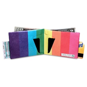 May include: Open rainbow-colored wallet with a vertical stripe design. The wallet is made of a durable material and features multiple card slots and a bill compartment. The wallet is open, revealing cash and cards.