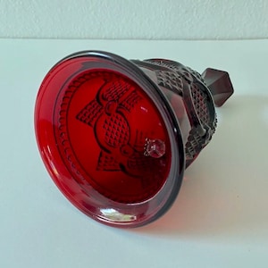 Puede incluir: Una campana de vidrio roja con un dise&ntilde;o detallado. La campana tiene una superficie texturizada y una peque&ntilde;a perilla en la parte superior.