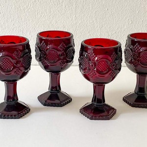 Puede incluir: Juego de cuatro copas de vidrio rojo rub&iacute; con un dise&ntilde;o texturizado en relieve. Las copas tienen una copa redonda y una base hexagonal.