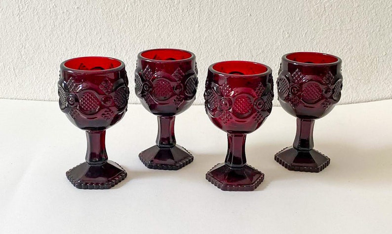 Puede incluir: Juego de cuatro copas de vidrio rojo rub&iacute; con un dise&ntilde;o texturizado en relieve. Las copas tienen una copa redonda y una base hexagonal.
