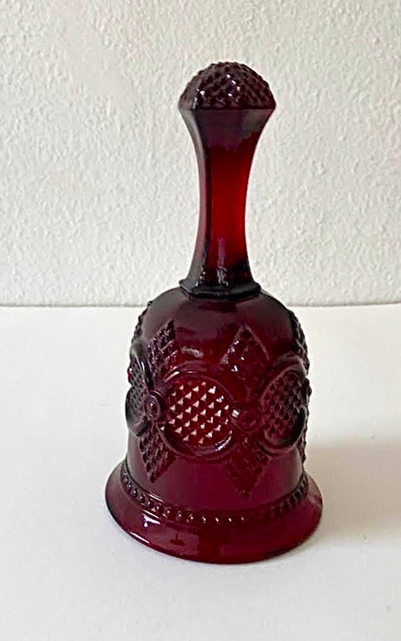 Puede incluir: Una campana de vidrio roja con un patr&oacute;n decorativo. La campana tiene una base ancha y un cuello estrecho.