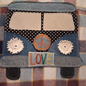 May include: A denim fabric applique shaped like a van, featuring a black and white polka dot panel, two white crocheted flower accents, an orange peace sign, and a rectangular patch with the embroidered word LOVE in multi-colored thread.