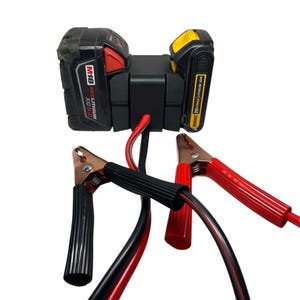 Puede incluir: Un arrancador de batería negro con cables de arranque rojo y negro. El arrancador de batería funciona con una batería Milwaukee M18 RED LITHIUM XC 5.0.