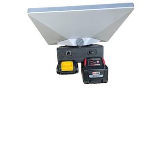 Könnte beinhalten: Ein graues und weißes geometrisches Gerät mit schwarzer Basis, mit einem gelben Akku und einem rot-schwarzen M18 XC8.0 Akku. Das Gerät hat einen Netzschalter und einen Anschluss.