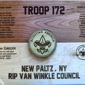 Puede incluir: Una placa de madera con el texto "TROOP 172" y "NEW PALTZ, NY RIP VAN WINKLE COUNCIL". La placa también presenta el Juramento Scout, la Ley Scout y el emblema del Scoutmaster.