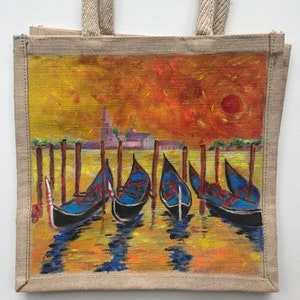 May include: A jute tote bag featuring a painted scene of gondolas on a canal in Venice, Italy. The scene is painted in shades of yellow, orange, red, blue, and green. The gondolas are lined up along the canal, with the setting sun in the background.